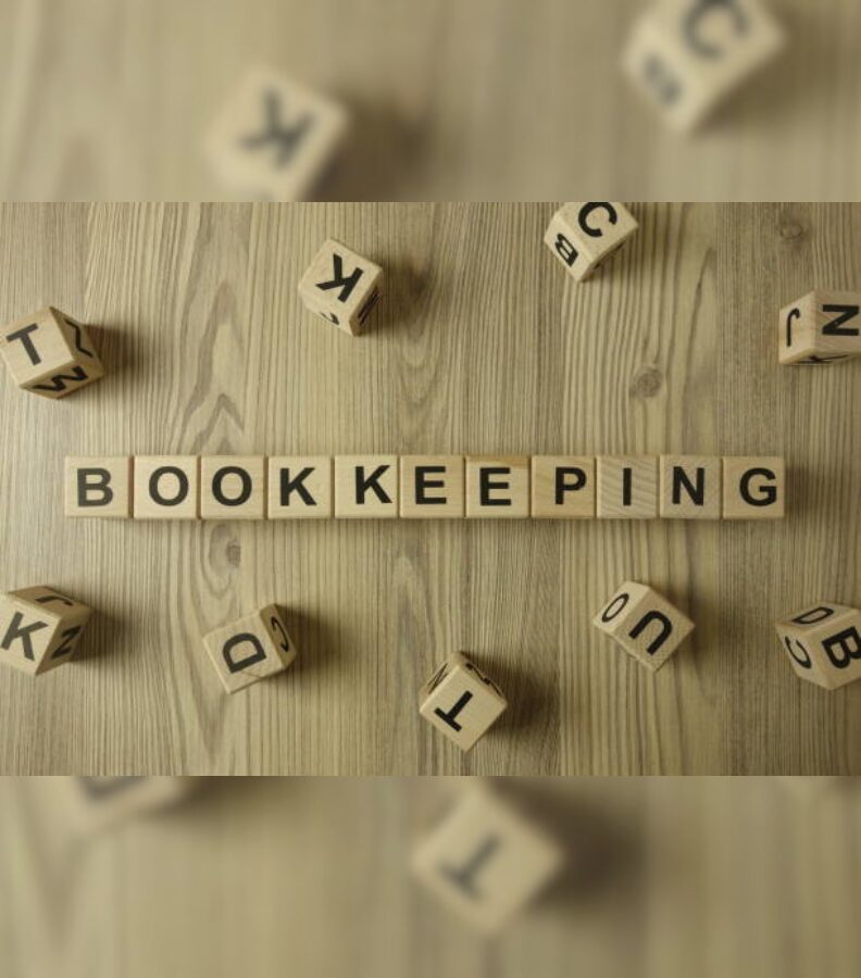 Wooden blocks spelling out 'BOOKKEEPING' on a wooden surface.